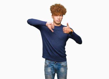 Yakışıklı genç afro saçlı yapıyor başparmak yukarı ve aşağı, anlaşmazlık ve anlaşma ifade. Deli çatışma