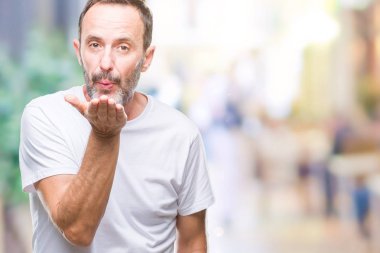 Bir öpücük el ile güzel ve seksi olmak hava üfleme kamera bakarak izole arka plan üzerinde beyaz t-shirt giyen orta yaş ağarmış komuta sizde. Aşk ifade.