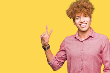 Mutlu yüz zafer işareti yaparken kameraya göz kırpıyor ile gülümseyen afro saçlı Genç yakışıklı iş adamı. İki numaralı.