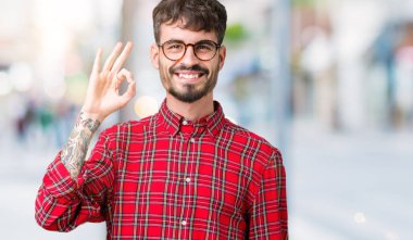 İzole arka plan el ve parmaklar ok işaretiyle yapıyor olumlu gülümseyen üzerinde gözlük takan yakışıklı delikanlı. Başarılı ifade.