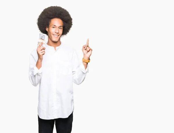 年轻的非洲裔美国人与非洲头发举行了一堆美元非常高兴用手和手指指向一边 — 图库照片