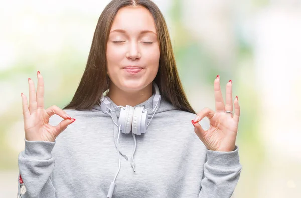 年轻美丽的高加索学生妇女戴着耳机在孤立的背景放松和微笑闭着眼睛做冥想手势与手指 瑜伽概念 — 图库照片