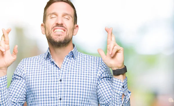 Yakışıklı iş adamı mavi ile gülümseyen geçiş parmakları ile umut ve gözleri kapalı gözler. Şans ve batıl kavramı.