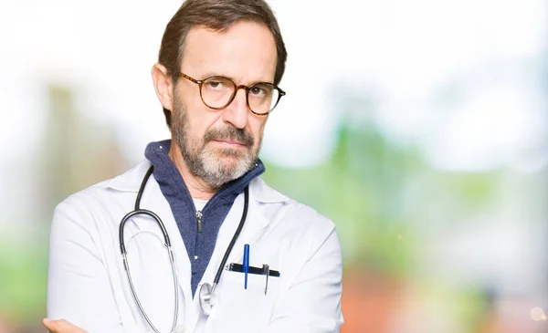 Handsome middle age doctor man wearing medical coat skeptic and nervous, disapproving expression on face with crossed arms. Negative person.