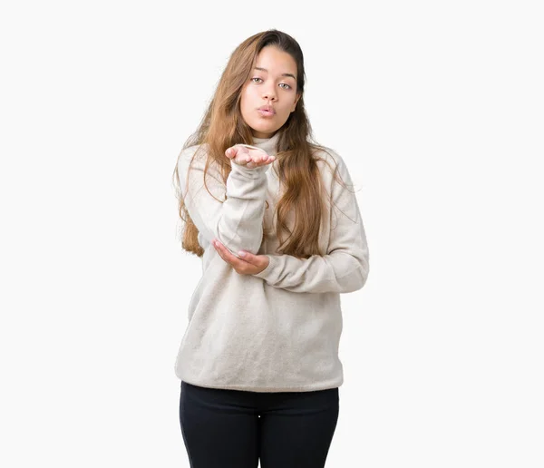 若い美しいブルネット女性のオンエアされて素敵なセクシーな手でキスを吹いてカメラ目線孤立の背景にタートルネックのセーターを着ています 愛情表現 — ストック写真