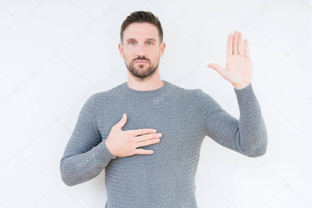 Young handsome man wearing casual sweater over isolated background Swearing with hand on chest and open palm, making a loyalty promise oath