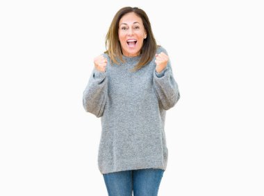 İzole arka plan üzerinde kutluyor kış kazak giyen güzel orta yaş kadın şaşırttı ve başarı için kaldırdı kollarını açarak hayret ve gözleri açık. Kazanan kavramı.