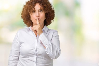 Dudaklarında parmak ile sessiz olmanı izole arka plan güzel orta ager üst düzey businees kadın. Sessizlik ve gizli kavramı.