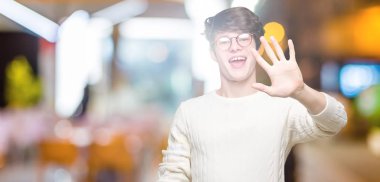 Gösterilen arka plan üzerinde gözlük takan genç yakışıklı adam izole ve parmakları ile işaret kendinden emin ve mutlu gülümseyerek süre beş numara.