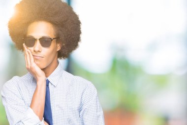 Genç Afro-Amerikalı iş adamı düşünme seyir yorgun ve sıkılmış depresyon sorunları ile güneş gözlüğü takıyor afro saçlı silah geçti.