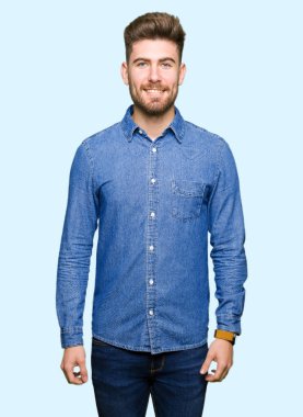 Yüzünde mutlu ve güzel bir gülümseme ile rahat kot gömlek giymiş genç yakışıklı sarışın adam. Şanslı kişi.