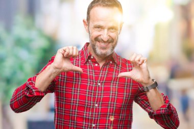 Orta yaş ağarmış komuta sizde yüzünde gülümseme ile kendinden emin görünüyorsun, kendini gururlu ve mutlu parmakları ile işaret izole arka plan üzerinde.