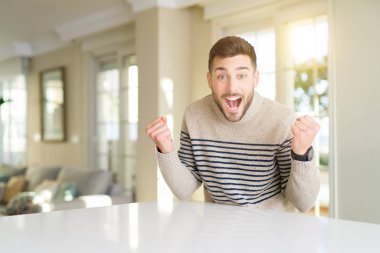 Genç yakışıklı adam evde geçirilen silahlarla şaşırmış ve başarı için hayran kutluyor ve gözleri açık. Kazanan kavramı.