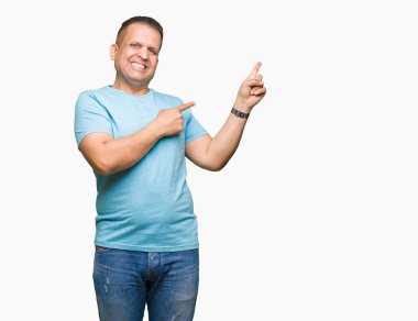 Orta yaş Arap adam gülümseyerek ve iki elleri ve parmakları ile tarafına işaret kamera bakarak izole arka plan üzerinde mavi t-shirt giyen.
