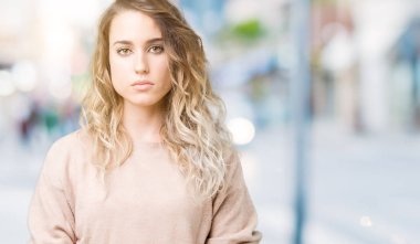Sweatershirt üzerinde giyen genç güzel sarışın kadın arka plan gevşek yüzünde ciddi bir ifade ile izole. Basit ve doğal kameraya bakıyor.