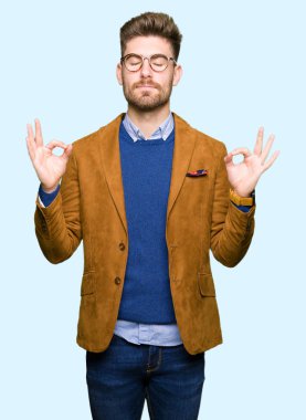 Genç yakışıklı iş adam gözlük rahatla ve gülümseyen gözlerle kapalı parmak jestle meditasyon yapıyor. Yoga kavramı.