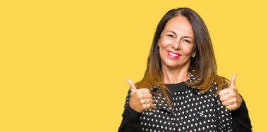 Moda ceket başarı işareti el ile pozitif jest yapıyor giyen güzel orta yaş kadın başparmak gülümseyen ve mutlu. Neşeli bir ifadeyle, kazanan jest kameraya bakıyor.