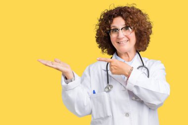 Orta ager kıdemli doktor kadın hayrete ve el ile sunulması ve parmak ile işaret ederken kameraya gülümseyen izole arka plan.