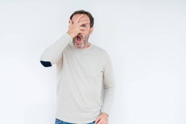 Mahcup ifadeyle parmaklarımın arasından bakan zarif üst düzey adam yüz ve gözler el ile kapsayan şok bakmak izole arka plan üzerinde.