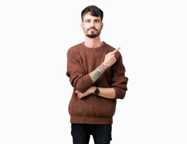 Genç yakışıklı adam giyen kış kazak izole üzerinden reklam, ciddi ve sakin yüz gösterilen yan el parmak ile işaret arka plan