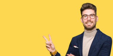 Mutlu yüz zafer işareti yaparken kameraya göz kırpıyor ile gülümseyen gözlüklü genç yakışıklı iş adamı. İki numaralı.