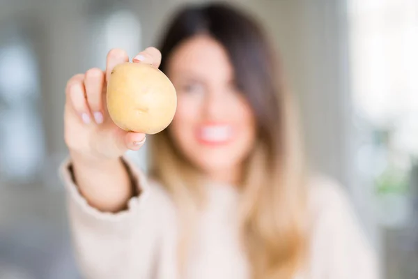 年轻美丽的女人拿着新鲜的土豆在家里 一个快乐的脸站着 面带微笑 自信的微笑显示牙齿 — 图库照片