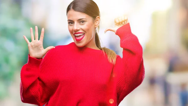 Young beautiful business woman wearing winter sweater over isolated background showing and pointing up with fingers number six while smiling confident and happy.
