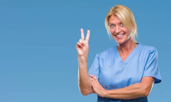 中年金发女子穿医生护士制服在孤立的背景微笑与快乐的脸眨眼在相机做胜利标志 第二个 — 图库照片