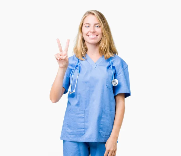 上医療ユニフォーム身に着けている美しい若い医師女性分離を示す背景と自信を持って 幸せな笑みを浮かべている間 つ番号を指で上向き — ストック写真