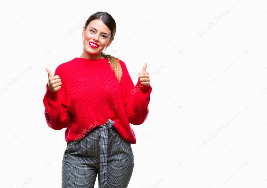 Young beautiful business woman wearing winter sweater over isolated background success sign doing positive gesture with hand, thumbs up smiling and happy. Looking at the camera with cheerful expression, winner gesture.