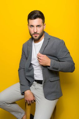 Possing oturan ve sarı izole arka plan üzerinde modelleme yakışıklı delikanlı