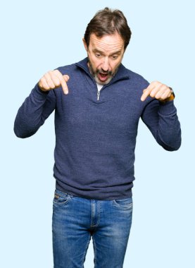 Orta yaş yakışıklı adam kazak giyiyor aşağı reklam, sürpriz yüz ve açık ağız gösterilen parmakları ile işaret