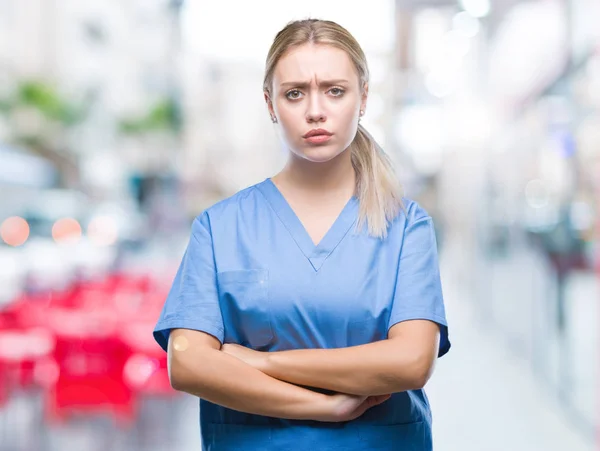 Young blonde surgeon doctor woman wearing medical uniform over isolated background skeptic and nervous, disapproving expression on face with crossed arms. Negative person.