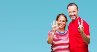 Orta yaş İspanyol çift aşık gösterilen ve parmakları ile işaret izole arka plan üzerinde kendinden emin ve mutlu gülümseyerek süre sekiz numara.