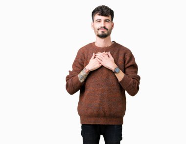 Yakışıklı delikanlı ile gülümseyen izole arka plan üzerinde kış kazak giyen kapalı gözler ve yüzünde minnettar jest ile göğüs üzerinde eller. Sağlık kavramı.