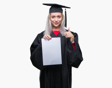 İzole arka plan üzerinde derecesi büyük gülümseme ok işareti, başparmak ile parmak, mükemmel işareti yapıyor ile mutlu tutarak yüksek lisans üniforma giyen genç sarışın kadın