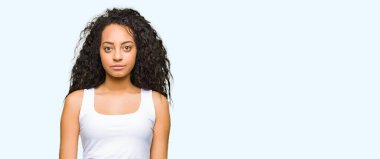 Yüzünde ciddi bir ifade ile kıvırcık saçlı Genç güzel kız. Basit ve doğal kameraya bakıyor.