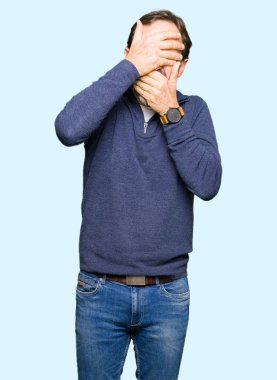 Orta yaş yakışıklı adamın bir kazak kapsayan gözleri giydiğini ve şaşırttı ve şok ellerle ağız. Duygu gizleme