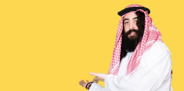 Geleneksel keffiyeh eşarp açık el ile doğal gülümseyen girmek için davet giymiş uzun saçlı Arap iş adamı
