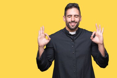 Genç Hıristiyan rahip izole arka plan üzerinde dinlenmek ve gülümseyen gözlerle parmak ile meditasyon jest yapıyor kapalı. Yoga kavramı.