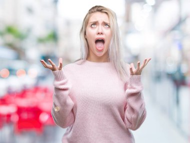 Üzerinde kış kazak giyen genç sarışın kadın arka plan deli izole ve deli bağırarak ve agresif ifade ve silah kaldırdı bağırıyor. Hayal kırıklığı kavramı.