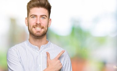 Genç yakışıklı adam neşeli bir gülümseme ile el ve parmak kadar yan yüzünde mutlu ve doğal ifade ile işaret eden yüz