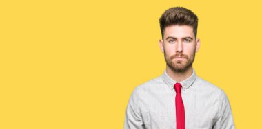 Genç yakışıklı iş adamı gevşek yüzünde ciddi bir ifade ile. Basit ve doğal kameraya bakıyor.