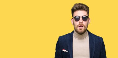 Genç yakışıklı zarif adam korkuyor ve şok sürpriz ifade, korku ve heyecan yüz ile güneş gözlüğü takıyor.