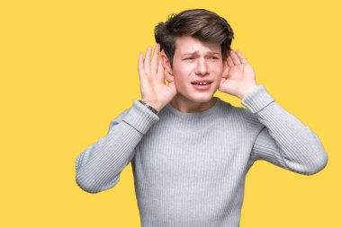 Her ikisi de dinliyoruz izole arka plan üzerinde kış kazak giyen genç yakışıklı adam kulak jest, dedikodu için meraklı eller. İşitme sorunu, sağır