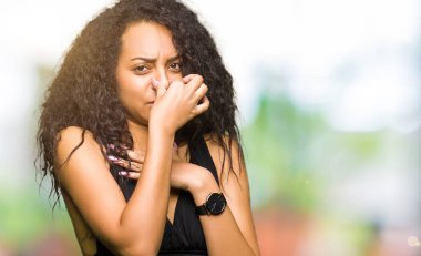 Kıvırcık saçlı bir şey pis ve iğrenç kokulu moda etek, dayanılmaz koku, holding nefes parmak ile burun üzerinde giyen genç güzel kız. Kötü kokuyor kavramı.