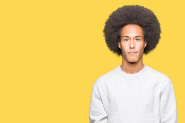 Afrikalı-Amerikalı genç afro saçlı sportif kazak gevşek ciddi ifade ile yüzünde giyiyor. Basit ve doğal kameraya bakıyor.