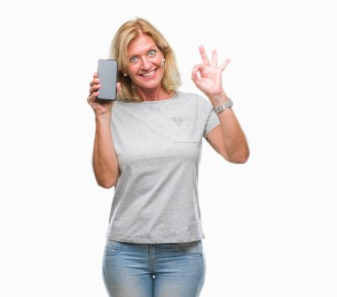 Orta yaş sarışın kadın gösteren boş ekran smartphone üzerinde parmak, mükemmel sembolü ile ok işareti yapıyor izole arka plan