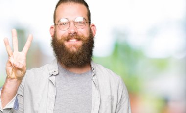 Kendinden emin ve mutlu gülümseyerek sırasında gösterilen ve parmakları ile işaret genç sarışın adam gözlük üçüncüsü.