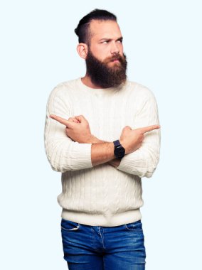 Kış kazak giyen genç hipster adam her iki parmak ile işaret eden, farklı yönde katılmıyorum